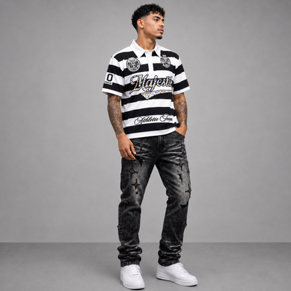 A man modeling a black and white striped polo shirt with 'Vitaforte' and 'Golden Arms' branding, paired with distressed black jeans and white sneakers, against a gray studio background.